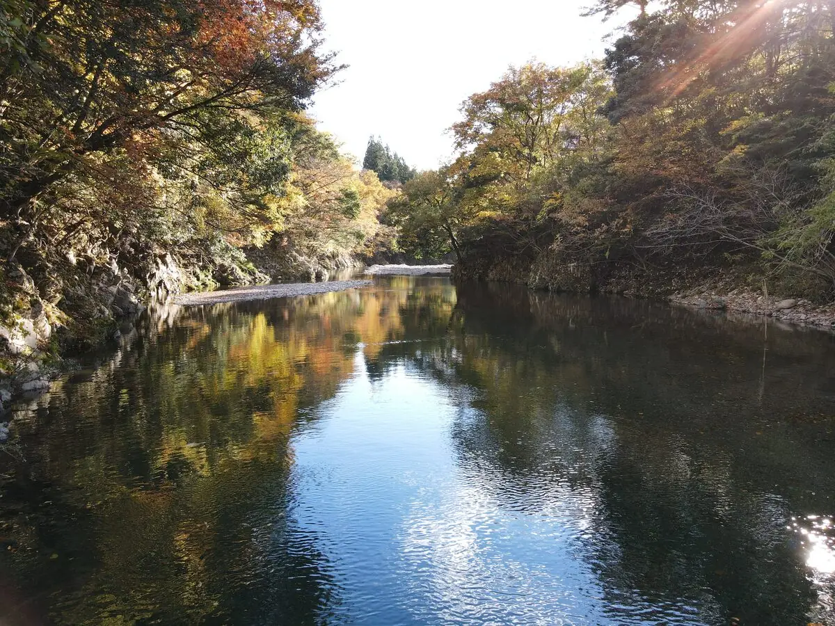 紅葉に包まれた渓谷と、水面に映る秋の色